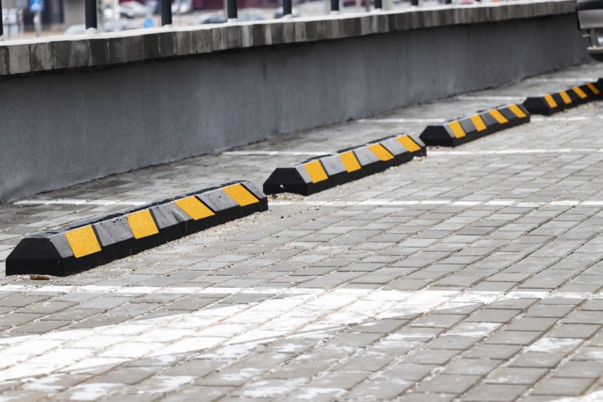 Pusty parking w dzielnicy mieszkalnej z żółtymi ogranicznikami parkowania dla samochodów. zbliżenie. Ogranicznik parkowania